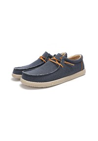 Mocassins en tissu bleu marine avec semelles en caoutchouc beige, présentant des lacets et des accents orange, un matériau texturé et un design décontracté.