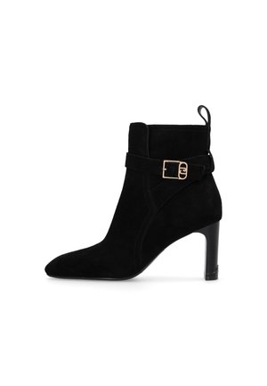 Black suede ankle boot with a pointed toe, sculpted heel, and an adjustable strap featuring a gold-tone buckle detail.