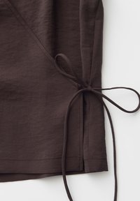 Dark brown fabric with a side tie closure forming a loose bow, showing stitched seams and a slight texture against a white background.