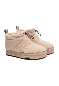 Bottines en peluche beige avec un extérieur texturé et ressemblant à de la polaire. Présentent un bout arrondi, des poignées de traction et un cordon de serrage ajustable pour un maintien sûr.