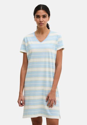 Donna che indossa un vestito a maniche corte con scollo a V e strisce orizzontali azzurro chiaro, bianco e giallo, in piedi davanti a uno sfondo uniforme.