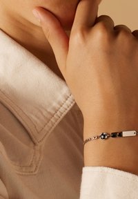 Zilveren schakelarmband met een platte rechthoekige hanger en een kleine accentvoetbal; beschikt over een delicate schakelontwerp en een gepolijste afwerking.