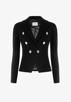 Blazer croisé noir à motif chevrons avec boutons métalliques, revers encadrés et une doublure intérieure lisse. Deux poches avant visibles.