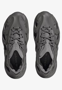 Atletiekschoenen in donkergrijs, met een gevormde bovenkant met golvende textuur, vetersysteem en gevoerde binnenkant.