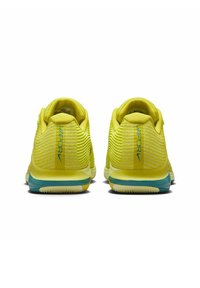 Zapatillas deportivas amarillas con parte superior de malla texturizada, diseño a rayas, detalles en color teal en la suela y la marca "VAPOR" en el talón.