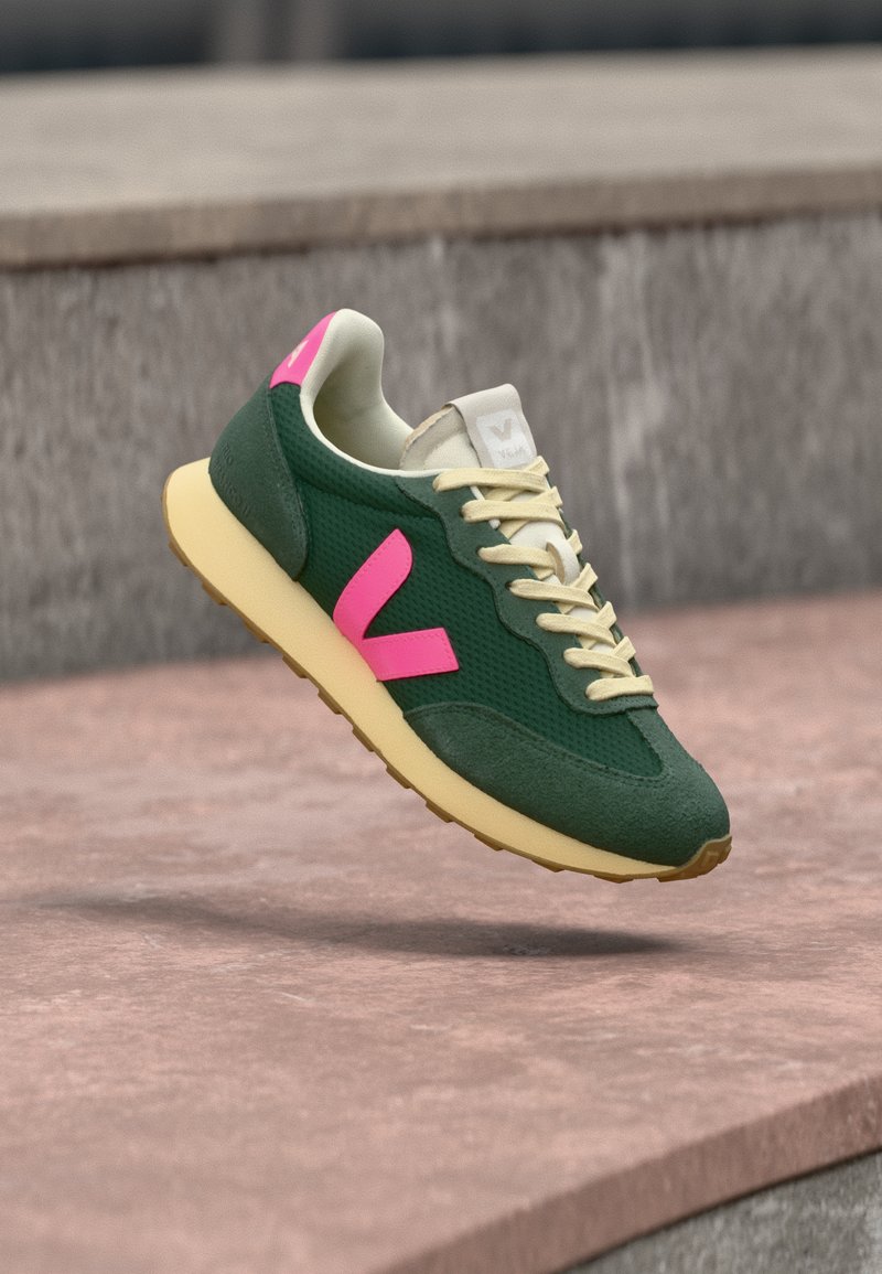 Πράσινο αθλητικό παπούτσι από δίχτυ με ροζ λεπτομέρειες και μπεζ κορδόνια. Διαθέτει υφασμένο επάνω μέρος και κίτρινη σόλα. Λογότυπο στη γλώσσα. Ελαφρύ σχέδιο.