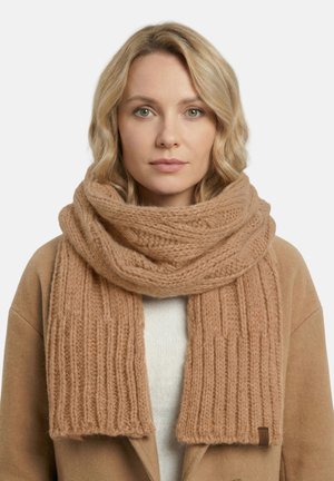 Beige neulottu huivi, jossa on ribbineulos, paksu lanka ja etikettitunniste. Kiedottu löysästi kaulan ympärille, luoden kodikkaan ilmeen.