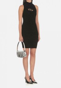 Vestito nero a coste con scollo all'americana e dettaglio cutout, abbinato a una borsa metallica argento e a tacchi neri a punta con accenti argentati.