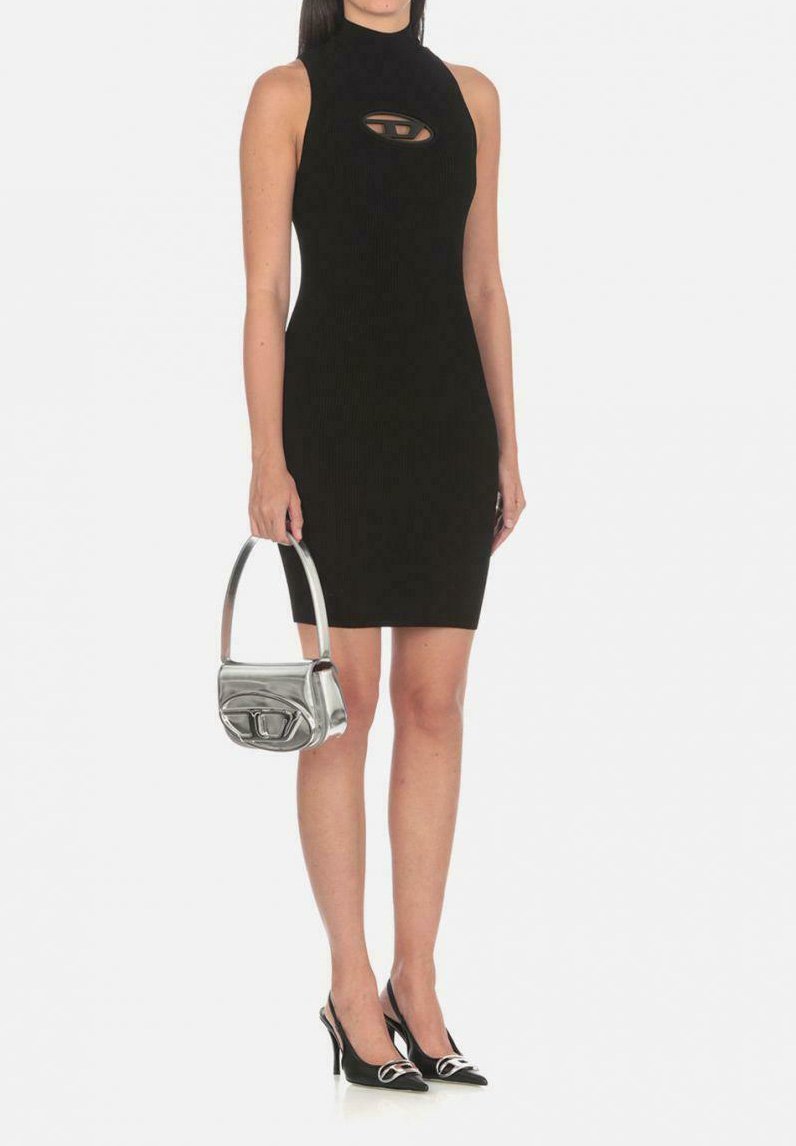 Vestito nero a coste con scollo all'americana e dettaglio cutout, abbinato a una borsa metallica argento e a tacchi neri a punta con accenti argentati.