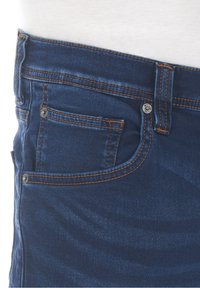 Vaqueros azul oscuro con un diseño clásico, costuras naranjas, un bolsillo frontal y botones de metal en la cintura y el bolsillo.