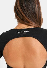 Schwarzes, geripptes Top mit offenem Rückendesign. Mit "SIXTH JUNE"-Markierung und einem "Designed in Paris"-Tag in der Nähe des Halsausschnitts.