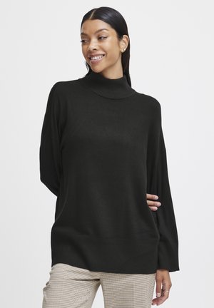 Schwarzer Rollkragenpullover mit lockerer Passform und gerippten Bündchen, kombiniert mit beigen karierten Hosen. Weiches Material und lässiges Design.