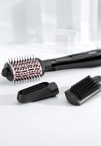 Styler per capelli elettrico con spazzola rotonda ventilata e due accessori neri per lo styling rimovibili su una superficie bianca.