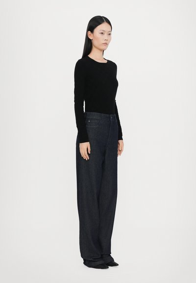Black long-sleeve top paired with high-waisted, wide-leg dark denim jeans. The fabric appears soft with a smooth finish. No visible patterns.