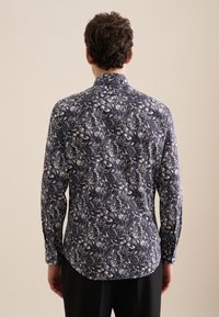 Camicia a maniche lunghe con sfondo blu navy e un motivo paisley in bianco, blu e verde. Realizzata in tessuto leggero, con colletto con bottoni.
