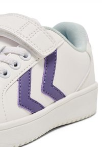 Sneaker bianco con accenti a forma di chevron viola, dotato di tomaia testurizzata, chiusura con lacci e una fascia con velcro per una calzata sicura.