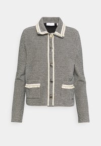 Chaqueta de tweed gris con cuello, cierre de botones, dos bolsillos y trimmings en color crema a lo largo de los bordes y bolsillos.