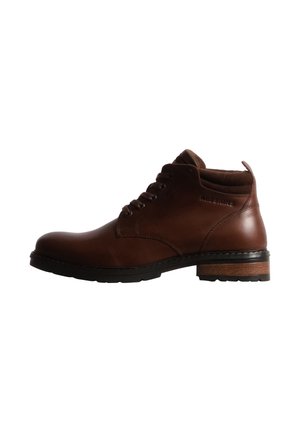 Bottine en cuir marron avec semelle noire, lacets à l’avant et petit talon, vue de profil.