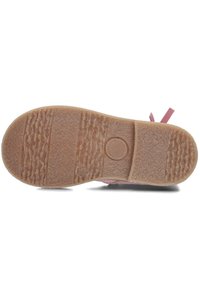 Pink shoe sole with textured rubber, featuring a patterned grip surface and a circular logo detail in the center.