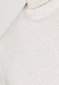 Helles beige Rollkragensweatshirt aus weichem, strukturiertem Stoff, mit enganliegendem Schnitt und geripptem Kragen für zusätzliche Wärme.