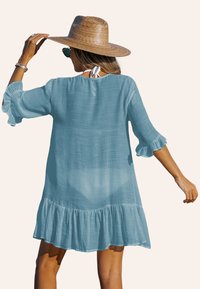 Robe bleu clair jusqu'aux genoux avec des manches à volants et un ourlet en plusieurs niveaux. Fabriquée en tissu léger, elle dispose d'une fermeture à nouer dans le dos.