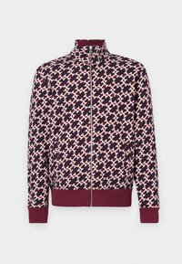 Chaqueta de cremallera con un patrón geométrico en burdeos, azul marino y crema. Presenta un cuello alto y puños y dobladillo acanalados. Textura de tela suave.