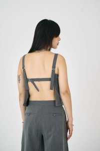 Grå ärmlös topp med justerbara band och öppen ryggdesign. Slät tyg med avslappnad passform, som matchas med grå byxor och fickor.