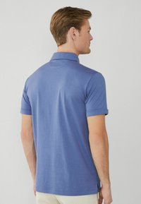 Polo shirt blu con maniche corte, colletto e un tessuto liscio e strutturato. Presenta un orlo dritto con spacchetti laterali.