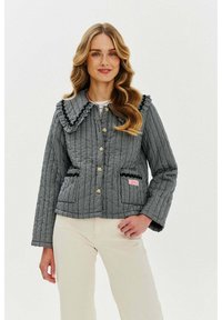 Černobílá kostkovaná prošívaná bunda s velkým volánovým límcem, předními knoflíky, dvěma kapsami a růžovým logem.