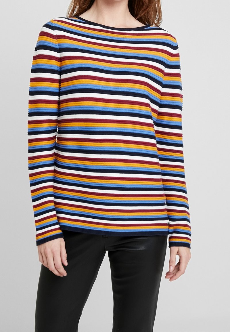 Haut à manches longues rayé avec des bandes horizontales rouges, jaunes, bleues et blanches, en tissu côtelé avec un col rond et des manches ajustées.