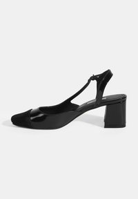 Chaussure à talon inclinée noire avec un bout arrondi, dotée d'un capuchon avant en suede texturé, d'une finition brillante en vernis et d'un talon carré.