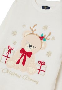 Weißer Fleecepullover mit einem süßen gestickten Bären mit Geweih, rotem Bogen und Stechpalme, umgeben von dekorativen Schneeflocken und Geschenken.