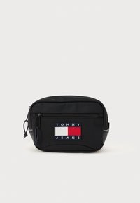 Sort stof talje taske med en frontlynlås, der har et flerfarvet broderet logo-patch med røde, hvide og blå rektangler.