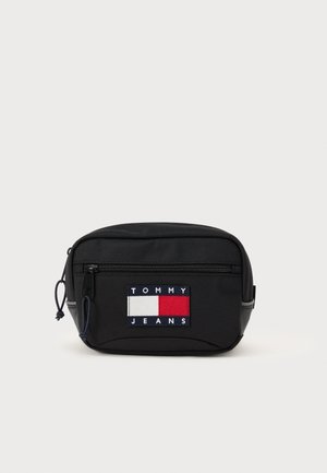 Zwarte stof heuptas met een voorzijde rits, voorzien van een multikleurige geborduurde logopatch met rode, witte en blauwe rechthoeken.