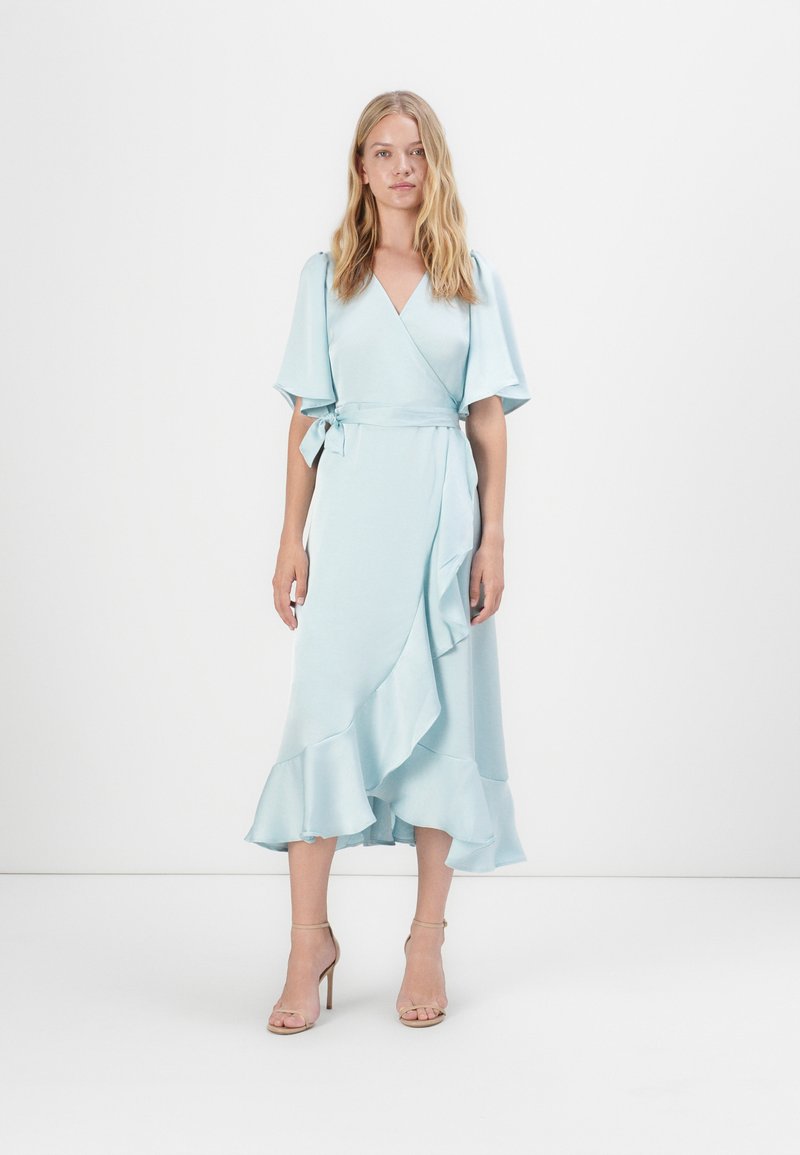 Vestido envolvente azul claro com mangas soltas e bainha com babados, feito de um tecido suave. Apresenta um fecho com laço na cintura.