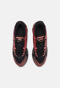 Black athletic shoes featuring a mesh upper with red accents, a streamlined design, and a rubber outsole with visible cushioning elements.