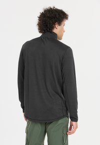 Dunkelgraues Langarmshirt mit hohem Kragen, glatter Textur und abgerundetem Saum. Besitzt eine lockere Passform und sichtbare Nahtdetails.