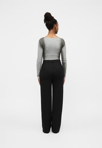 Γκρι μπλούζα με μακριά μανίκια και εφέ διαβάθμισης στο πίσω μέρος, συνδυασμένη με μαύρο παντελόνι φαρδιάς γραμμής, με ομαλή υφή και εφαρμογή κομμένη στα μέτρα.