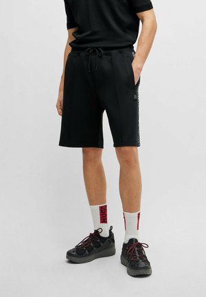 Svarta shorts i ett slätt tyg, med dragsko i midjan, sidofickor och en logotyp på vänster ben.