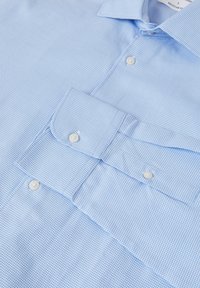 Camicia button-up azzurro chiaro con un piccolo motivo a quadretti, vestibilità regolare e bottoni bianchi. Presenta un colletto a pieghe e polsini con bottoni.