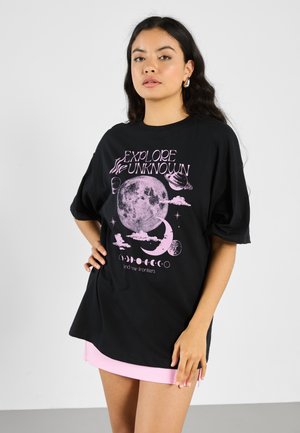Sort bomulds oversized T-shirt med et pink grafisk design af himmellegemer og teksten "UDFORSK DET UKENDTE." Korte ærmer.