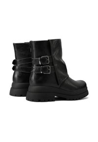 Stivali alla caviglia in pelle nera con due accenti a fibbia argentata, finitura texture, suola con piattaforma bassa e battistrada robusto per maggiore aderenza.