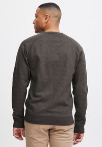 Donkergrijze sweatshirt met een textuurafwerking, ribgebreide manchetten en zoom, ronde hals en een klein logo-label aan de onderkant links.