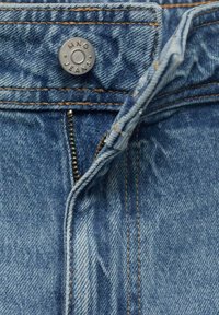 Traperice svijetloplave boje, s metalnim dugmetom s oznakom "MNG JEANS", kontrastnim šavovima i patentnim zatvaračem.