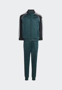 Träningsdräkt i mörk teal och svart, med en zip-up jacka med ribbade muddar och matchande avsmalnande joggare. Vita ränder framhäver ärmarna.