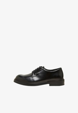 Černé kožené společenské boty s kulatou špičkou, šněrovacím designem a nízkým stohovaným podpatkem. Hladká textura a minimalistický styl.