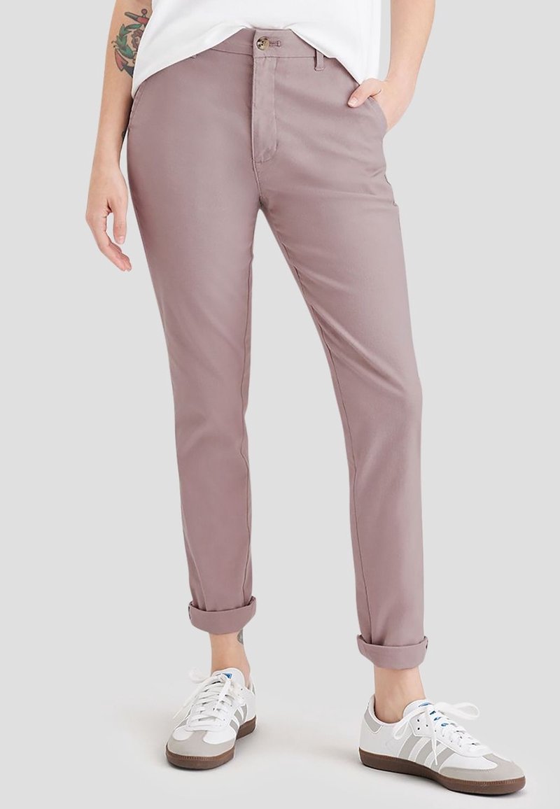 Ljus mauve byxor i slim fit, med uppvikt fåll, framfickor och knäppning, tillsammans med vita och grå sneakers.