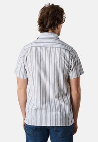 Camicia a maniche corte a righe in bianco e grigio, con una vestibilità rilassata, colletto a cancello e una leggera texture nel tessuto.