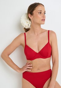 Set di bikini a coste rosse con bralette strutturata, spalline regolabili e slip a vita alta, caratterizzato da una texture liscia.