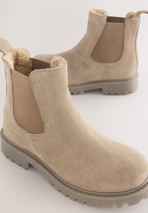 Die sandfarbenen Wildleder-Stiefeletten verfügen über elastische Seiteneinsätze, ein weiches Innenfutter und robuste Gummisohlen mit einem markant gemusterten Profil.